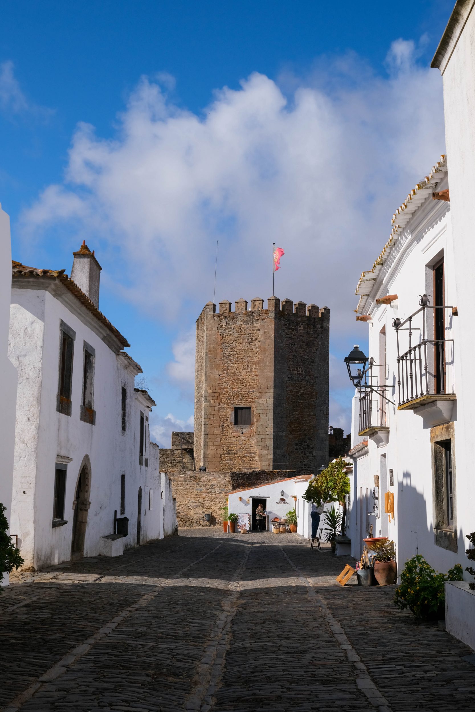 Foto di una strada, delle case bianche e il castello di Monsaraz, Portogallo.